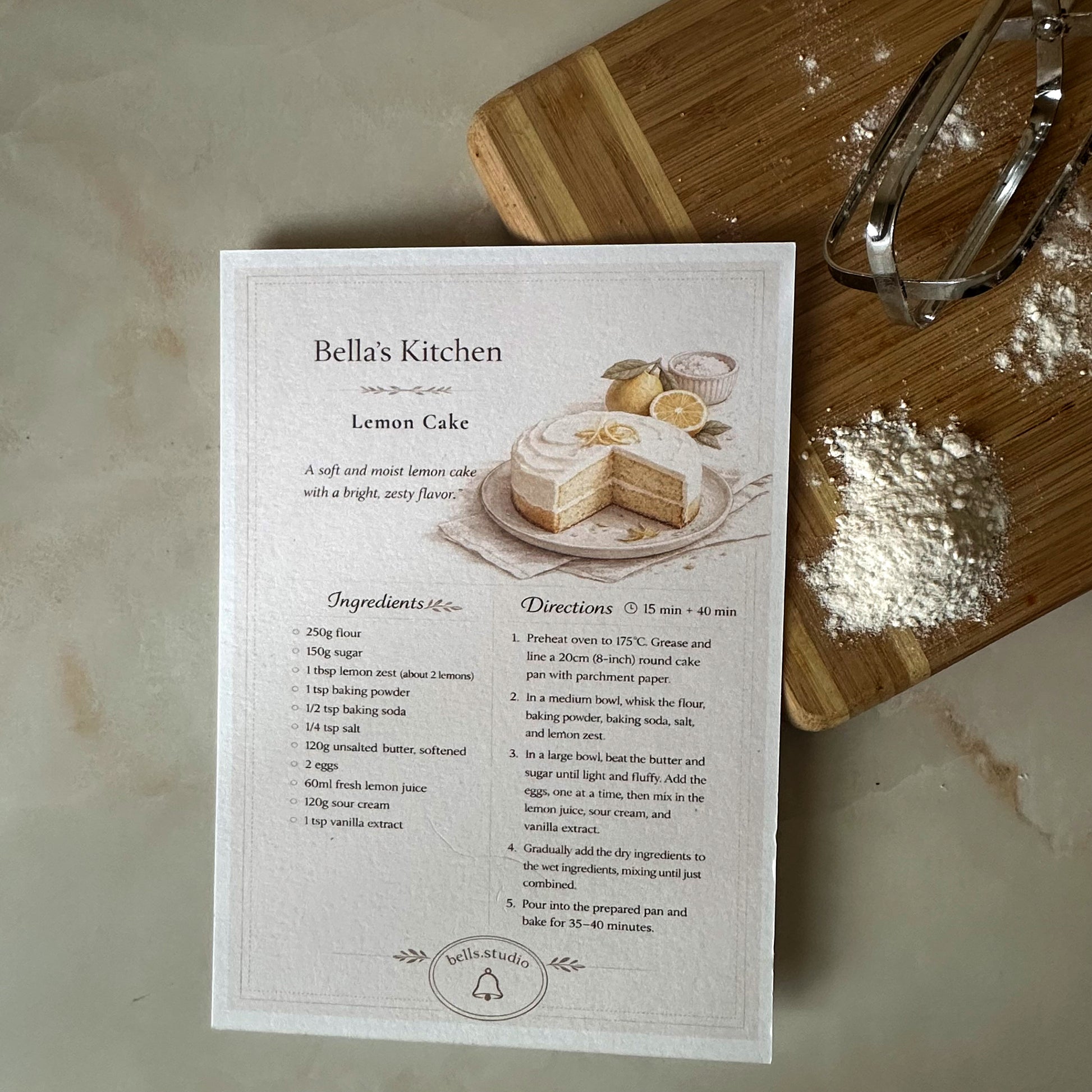 Recipe card for lemon cake on a kitchen counter with a wooden cutting board and flour.